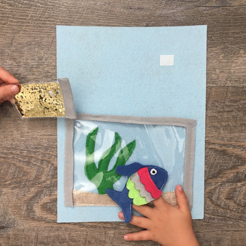 Get the free template to make this Fish Tank Quiet Book Page.  The fish is a finger puppet your toddler or preschooler will enjoy feeding with the glitter fish food.